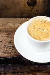 Closeup cup of espresso on old wooden table over grunge backgrou