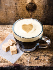 Small cup of espresso coffee in glass with heart drawning on fo