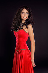 Fototapeta premium Beautiful happy smiling woman in red dress isolated on black bac