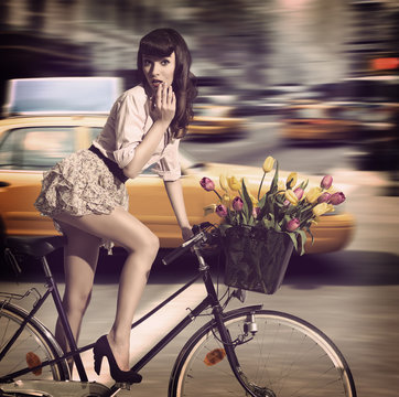 vintage woman on bicycle in a city street with taxi