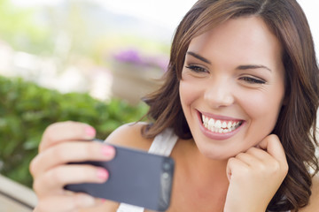 Pretty Adult Female Texting on Cell Phone Outdoors