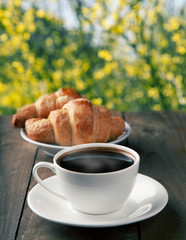 cup of coffee with croissants on nature background