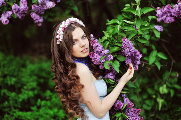 Beautiful young woman in lilac flowers, outdoors portrait