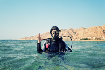 Obraz premium female diver shows a sign okay