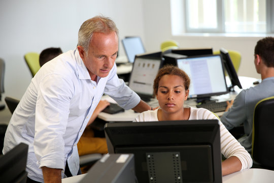 Teacher with student working on desktop computer