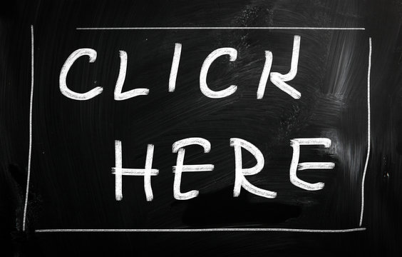 "Click here" handwritten with white chalk on a blackboard