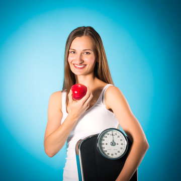 Young woman with scale under her arm and apple