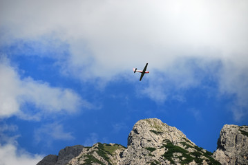 Fototapeta na wymiar Aeroplano tra le nuvole sopra i monti