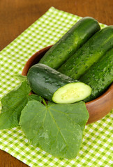 Tasty green cucumbers on color napkin, on wooden background