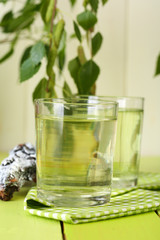 Glasses of birch sap on green wooden table