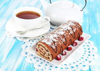Sweet roll with cup of tea on table close-up