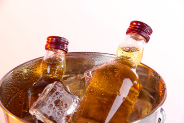 Minibar bottles in bucket with ice cubes, isolated on white