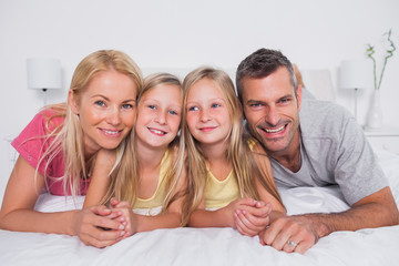 Portrait of parents lying in bed with their children