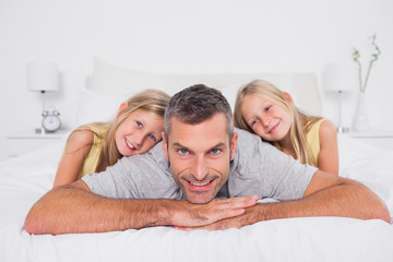 Cheerful man with his twins in bed