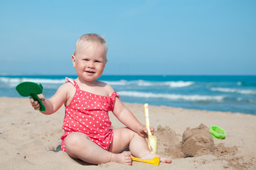Little girl sitting on sand at beach