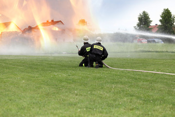 Strażacy gaszą poża budynków.