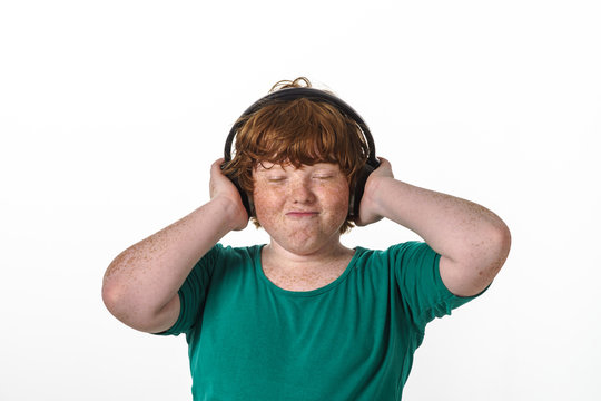 Freckled red-hair boy listening music.
