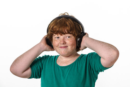 Freckled red-hair boy listening music.