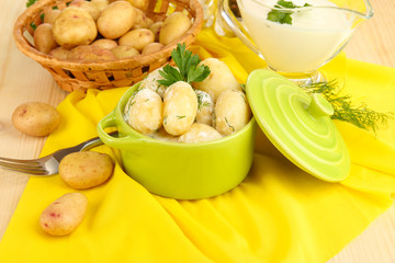Tender young potatoes with sour cream and herbs in pan