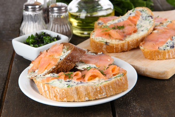 Fish sandwiches on cutting board and plate on wooden table