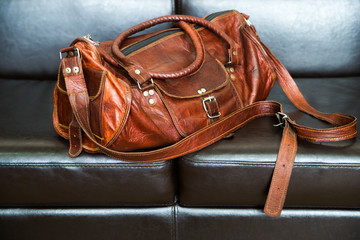 Luxury travel leather bag isolated on black leather sofa
