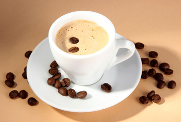 Cup of coffee with coffee beans on beige background