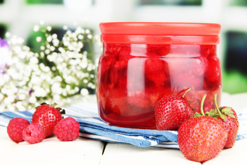 Home made berry jam on wooden table on bright background