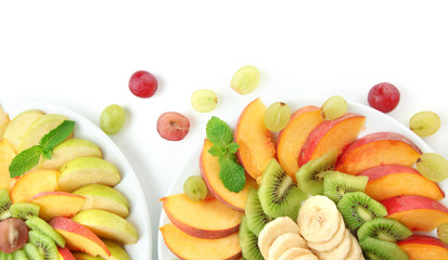 Assortment of sliced fruits on plates, isolated on white
