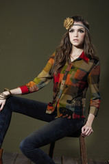 Fototapeta na wymiar Young fashion model in fashion clothes sitting wooden chair
