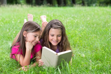 Zwei Mädchen lesen Buch auf der grünen Wiese