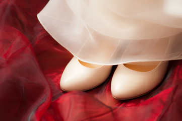 Brautschuhe und Brautkleid auf rotem Stoff