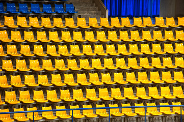 Plenty of yellow and blue plastic seats at stadium .