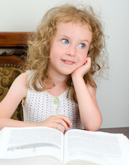Cute little smiling girl reading a book