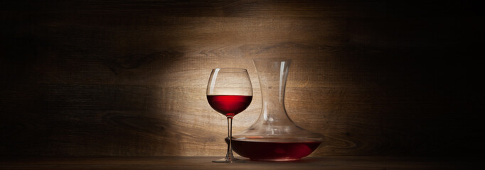 decanter with red wine and glass on a wood panorama background