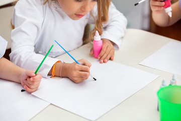 Girl Painting At Desk In Preschool