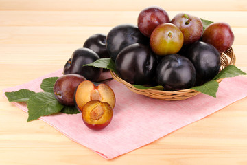 Rip plums on basket on wooden table