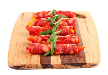 Salami rolls on wooden board, isolated on white