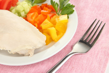 Boiled chicken breast on plate with vegetables close up