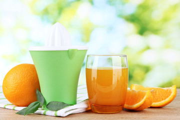 Citrus press, glass of juice and ripe oranges