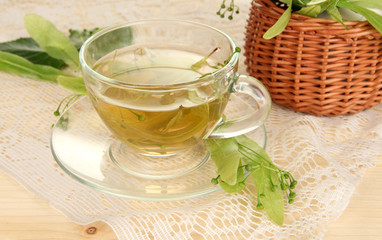 Glass cup of tea with linden on wooden table close-up