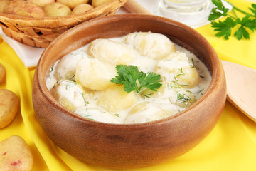 Tender young potatoes with sour cream and herbs in wooden bowl