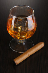 Brandy glass with ice on wooden background