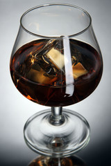 Brandy glass with ice on grey background
