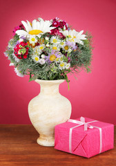 Beautiful bright flowers in vase with gift