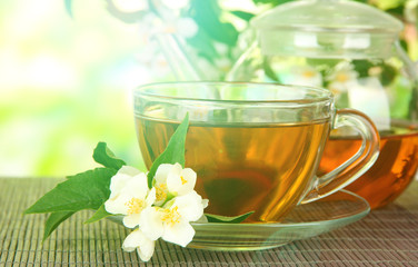 Cup of tea with jasmine, on bamboo mat, on bright background