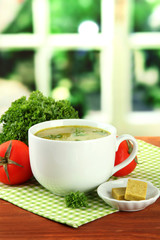 Cup of soup with bouillon cubes on wooden table