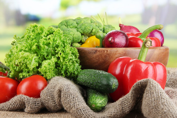 Fresh vegetables on burlap on bright background