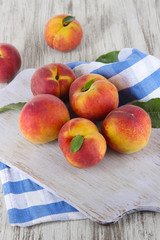 Peaches on board on napkin on table on wooden background