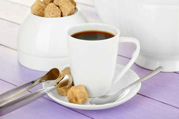 Cup of coffee, teapot and sugar-bowl on color wooden background