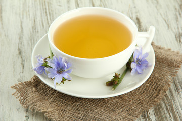 Cup of tea with chicory, on wooden background